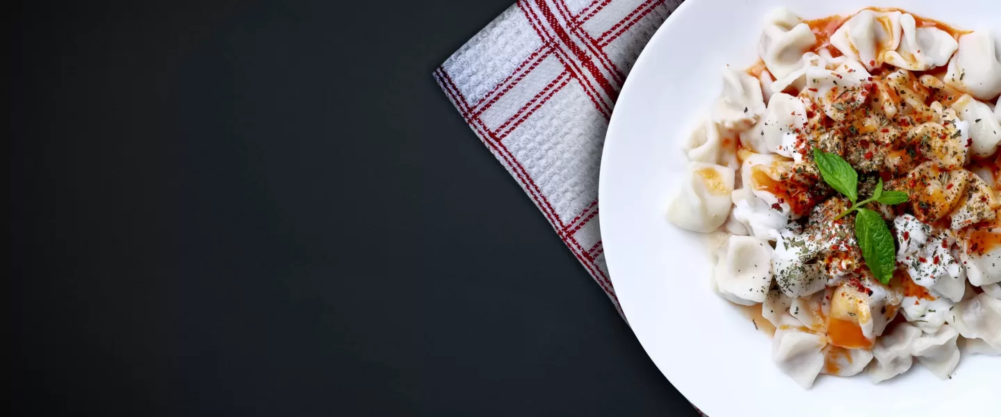 Plates of traditional Turkish food. Manti(Turkish ravioli) with tomato sauce.